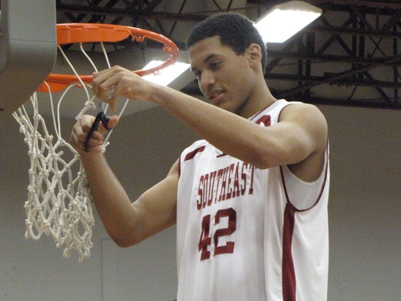 Jordan Thompson, freshman forward, cuts off a piece of the net after the Grenadiers won the KIAC Conference tournament title on their homecourt. 