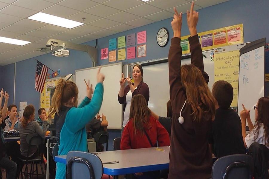(Standing) Shelby Royalty, education senior, teaches students a lesson about weathering in Susan Mosley’s fourth-grade classroom at Corydon Intermediate School. “We were making a W with our hands and then breaking it apart to show that weathering is the breaking of rocks,” Royalty said.