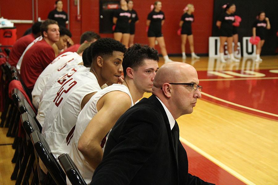 Jay Jones, assistant coach for the IUS men’s basketball team sits on the bench with players during the game against St. Catharine. This is Jones’ first year on staff.