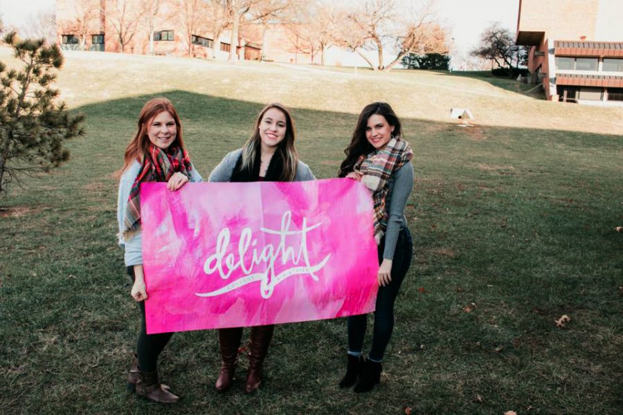 Kiersten Baird, strategic communication sophomore, left, Sydney Nalley, graphic design freshman, middle, and Alex Meador, business-marketing junior, right, pose with their Delight flag as they kick off the new organization on campus.