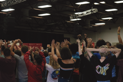 Students raise arms in the air as they do the wave at new student induction day.