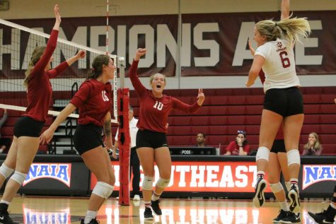 The Grenadier volleyball team celebrates after taking the third set against the defending national champions from Lindsey Wilson College. The Grenadiers would go on to lose the match 3-1. Photo by Tamar Kelly.