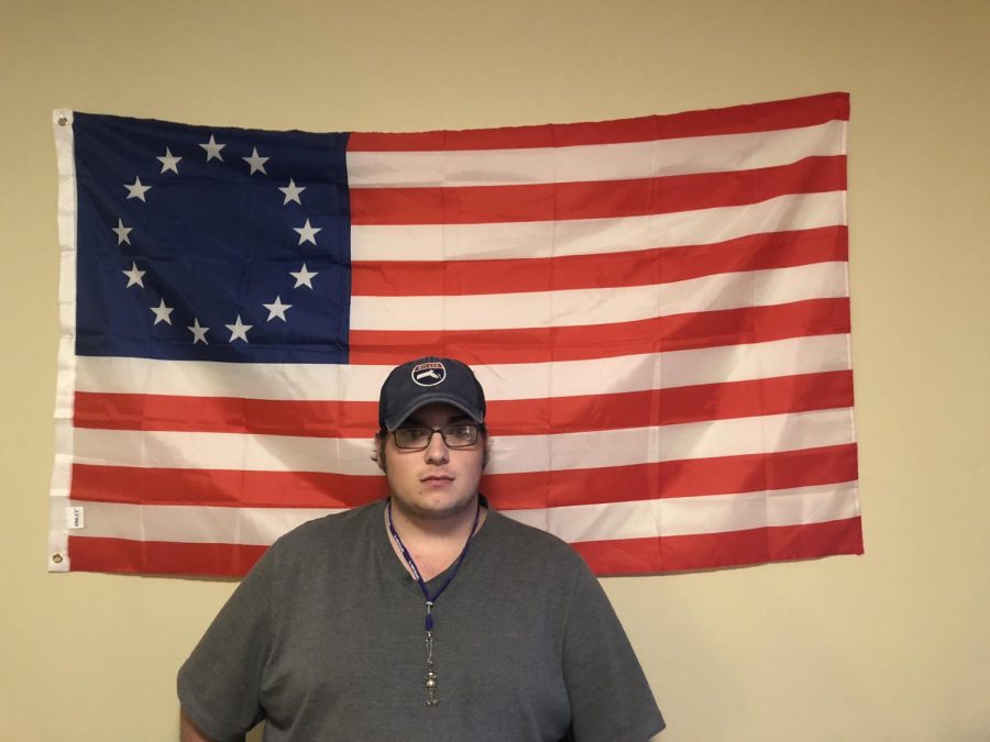 Austin Allen stands in front of the Thirteen Colonies flag that he brought to his IU Southeast dorm from his hometown in Massachusetts.