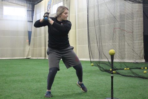 Sydney Seger loads herself up before hitting off a batting tee during batting practice