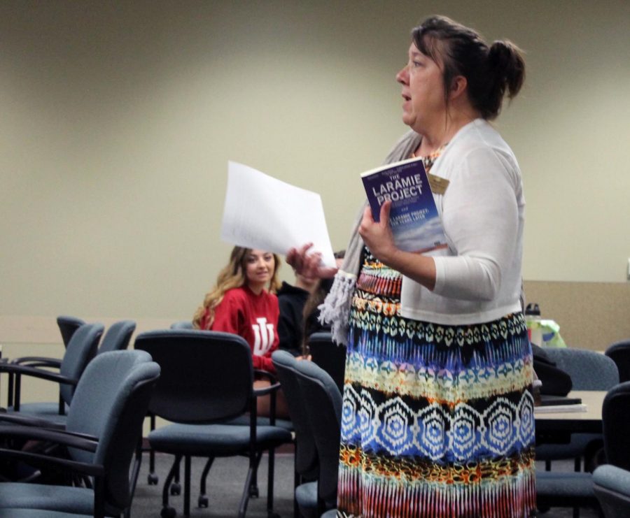 Kim Pelle, holding a physical copy of The Laramie Project, leads a discussion following the showing of the film.