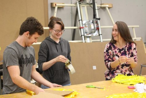 Three students in the art class find some humor in their work while creating the Harvest Homecoming Float. 