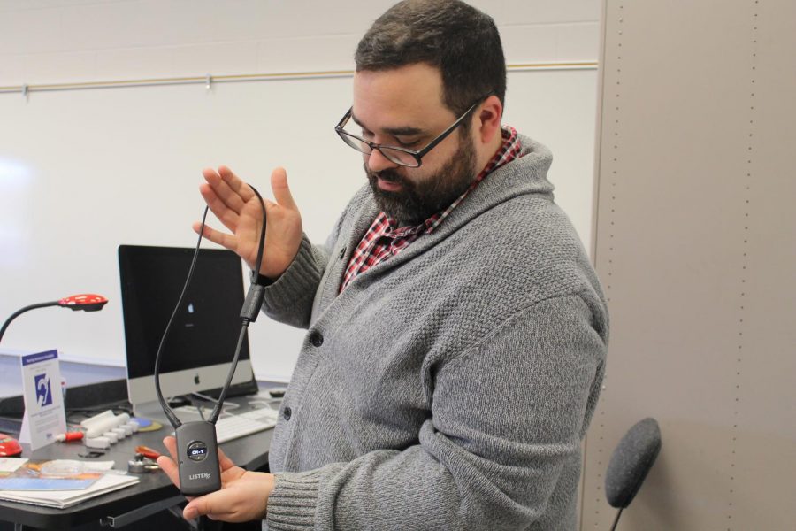 Danny Clements holds an assisted hearing device, which is one of the updated classroom technologies that has been implemented in the past few years thanks to the classroom budget.